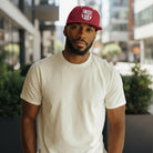 Man wearing a maroon FC Barcelona Bankroll Snapback Hat with white logo and a plain white t-shirt in an urban setting.