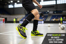 Joma Toledo indoor soccer shoes in black with neon yellow accents, worn by a player on a court